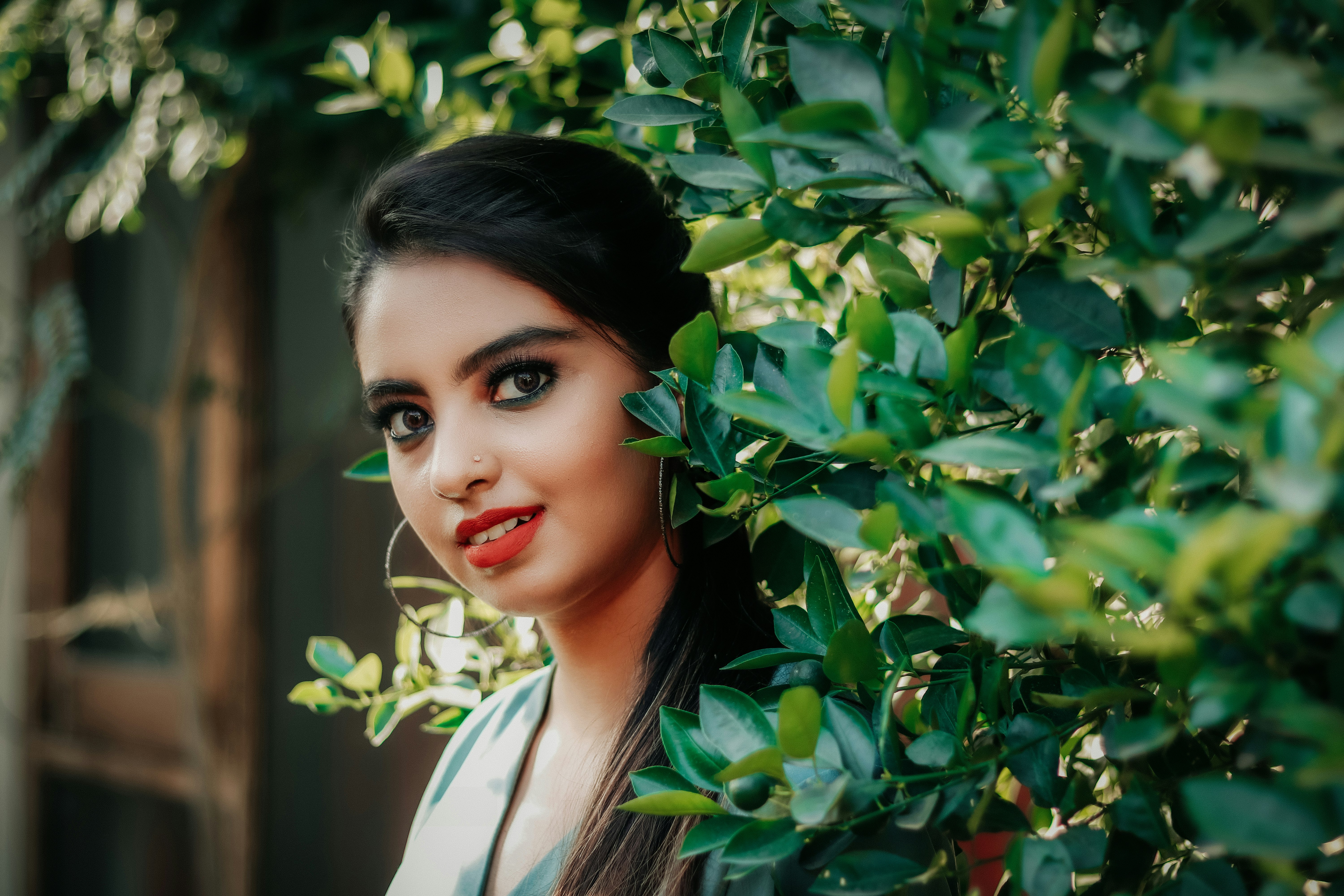 woman in white collared shirt standing beside green leaves